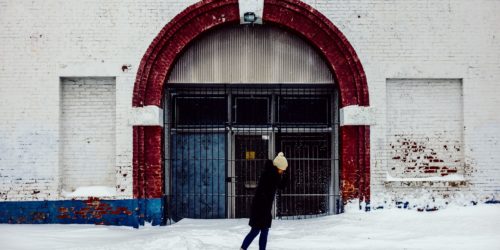 A woman walks in winter in front of a brick building