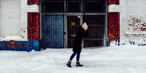 A woman walks in winter in front of a brick building